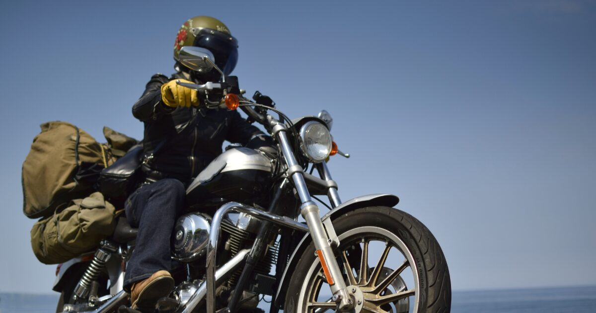 青空の下をツーリングする荷物を積んだバイクライダー