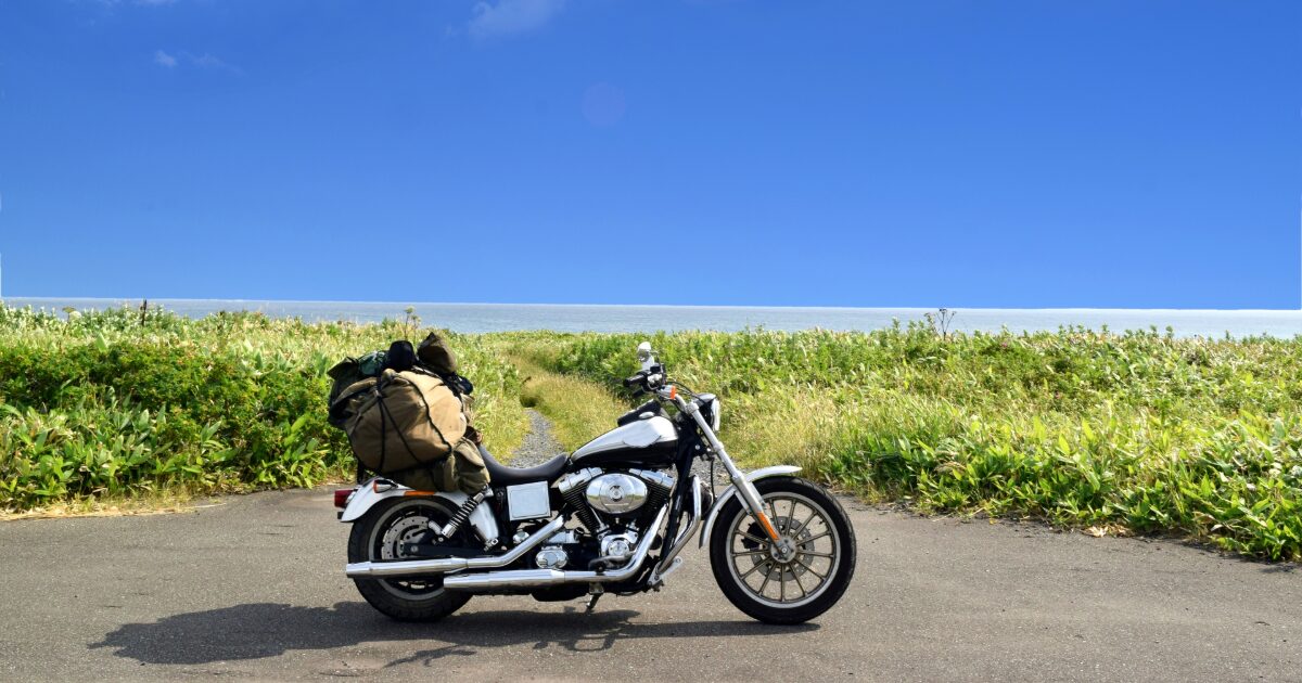 海沿いの草原と荷物を積んだバイクのツーリング風景
