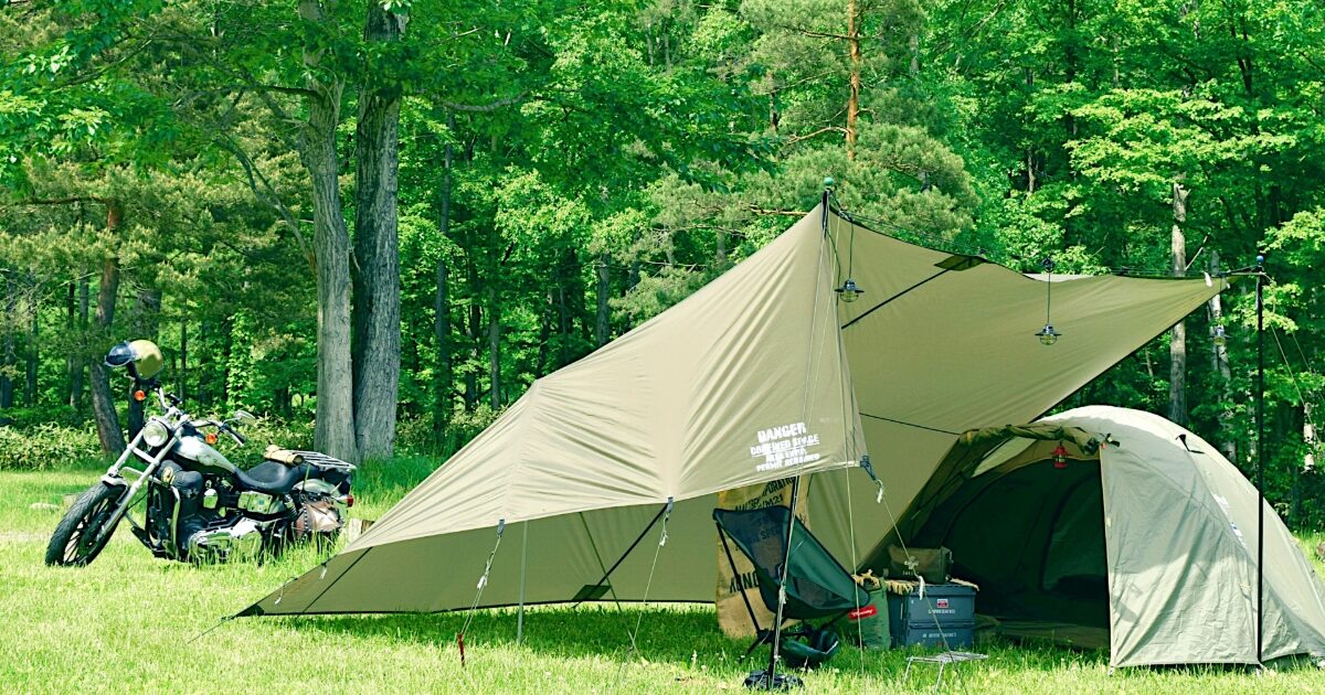 林間サイトでバイクとソロキャンプテントの風景