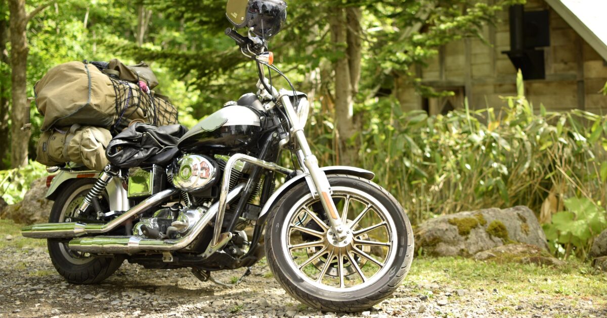 キャンプ道具を積んだハーレーダビッドソンと山小屋の風景